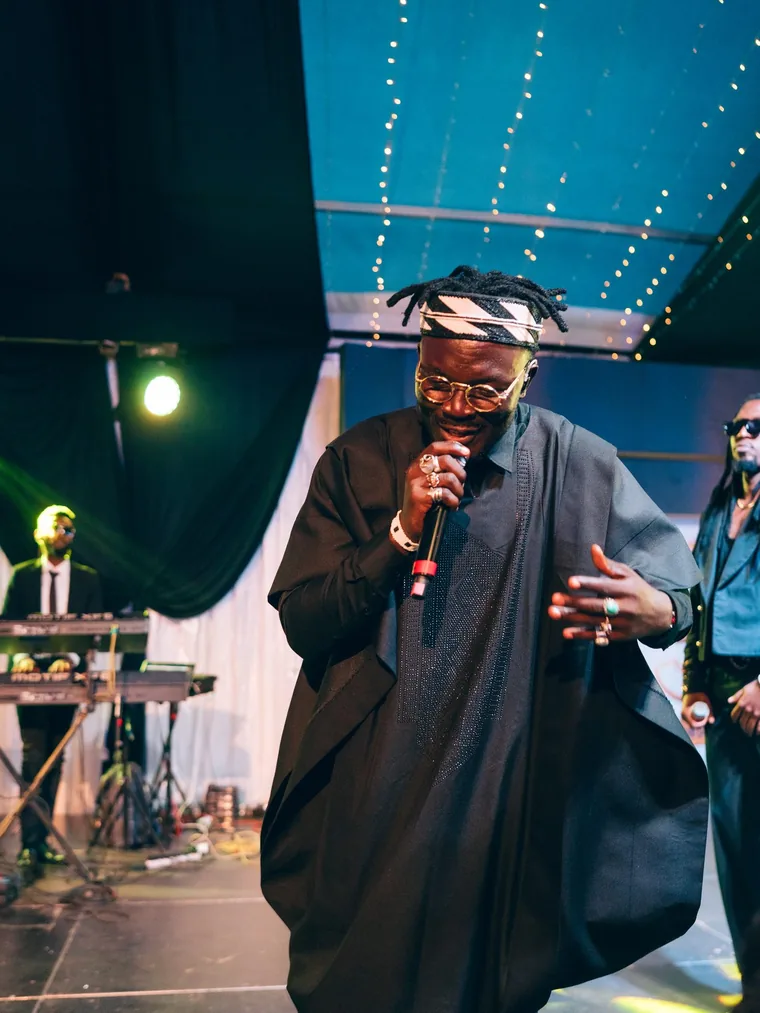 Kodong Klan vocalist in an agbada singing under blue light.